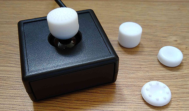 Small black box joystick with white top. For Game Control Mixer GCM100 interface.