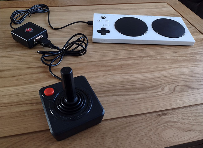 Atari CX40 classic 1970s joystick connected via a black box with OneSwitch logo on the top, to an Xbox Adaptive Controller.