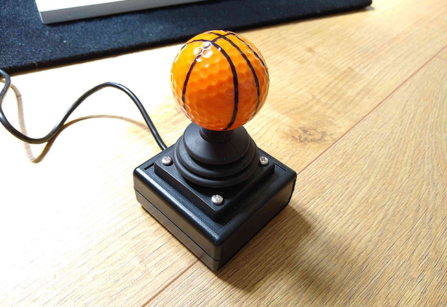 Bascket ball style golf ball on top of a OneSwitch Zik-Zak joystick with Xbox Adaptive Controller in the background.