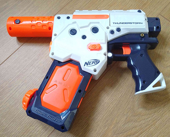 Orange, white and navy blue plastic water pistol with accessibility switch socket.