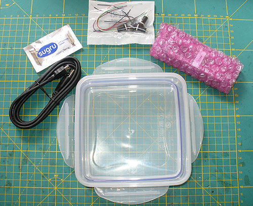 The basic parts needed from top left clockwise: 5g pouch of SUGRU rubber compound, switch sockets and wire, Ultimarc A-PAC PCB, Tupperware sandwich box, USB lead.