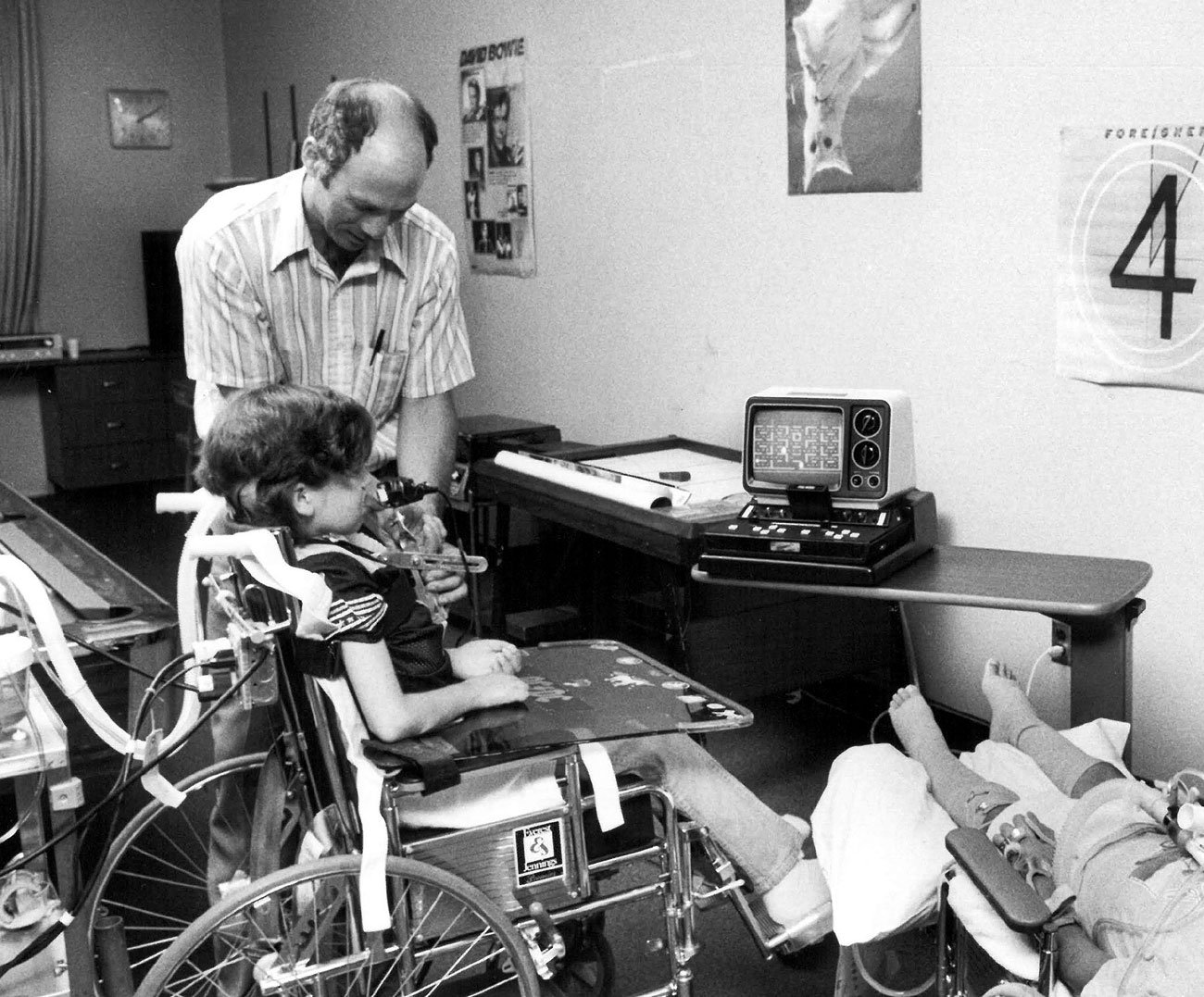 Ken Yankelevitz supporting Raymond Balsey play Pac-Man on an Atari VCS, using a mouth controller.