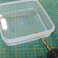 Image of the tupperware box being drilled for the switch socket.
